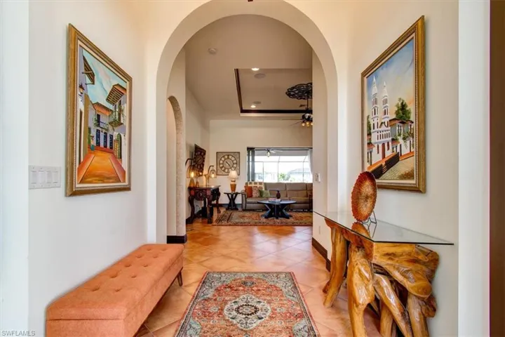 Hall featuring light tile patterned floors and a tray ceiling