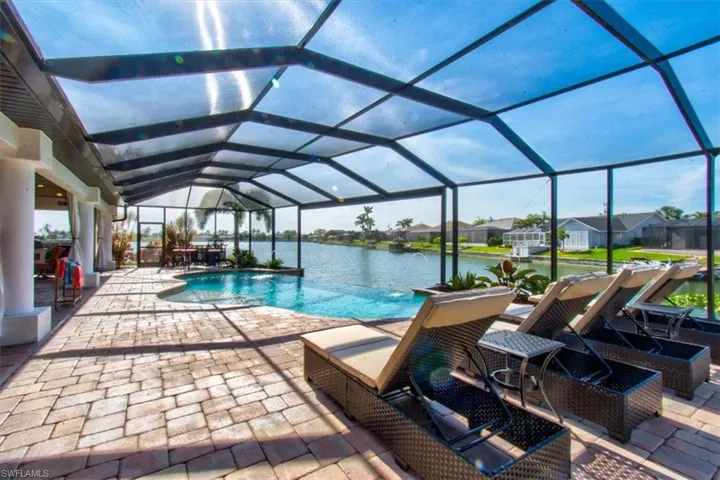 View of pool featuring pool water feature, a water view, a patio area, and a lanai