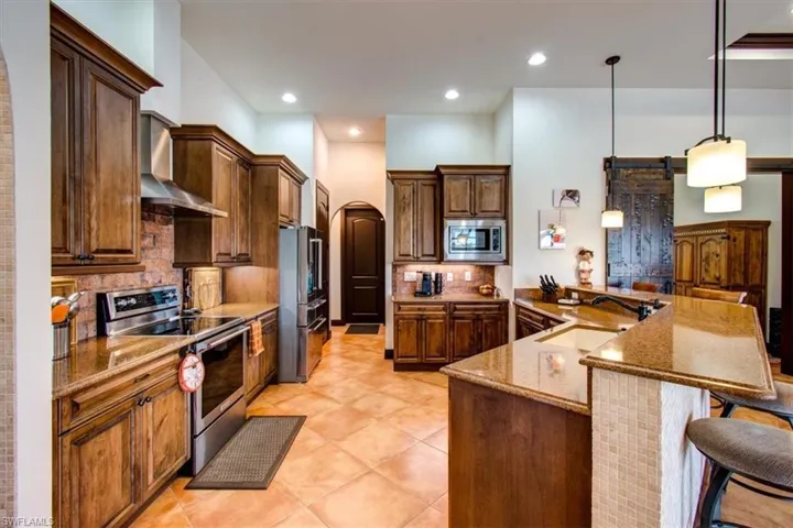 Kitchen featuring a barn door, sink, appliances with stainless steel finishes, and tasteful backsplash