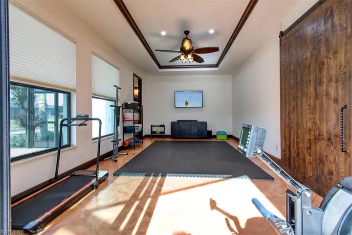 Exercise room featuring a tray ceiling and ceiling fan