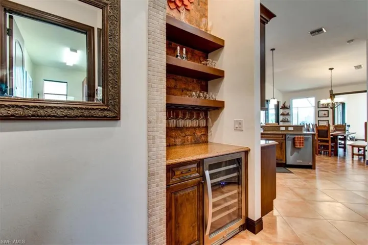 Bar with dishwasher, hanging light fixtures, wine cooler, built in features, and a chandelier