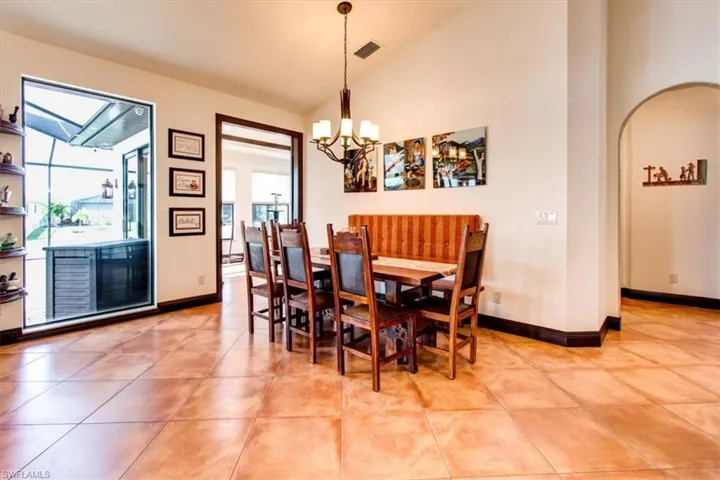 Dining space with a chandelier, light tile patterned floors, and lofted ceiling