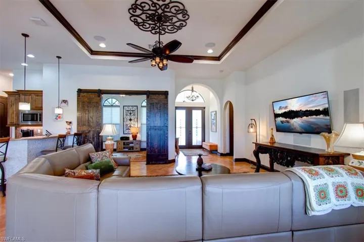Tiled living room with french doors, a raised ceiling, ceiling fan, and ornamental molding