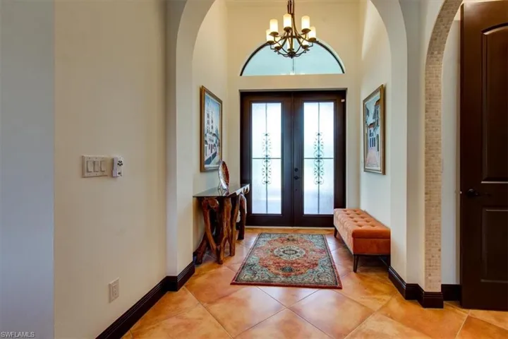 Entryway with an inviting chandelier, light tile patterned flooring, a high ceiling, and french doors