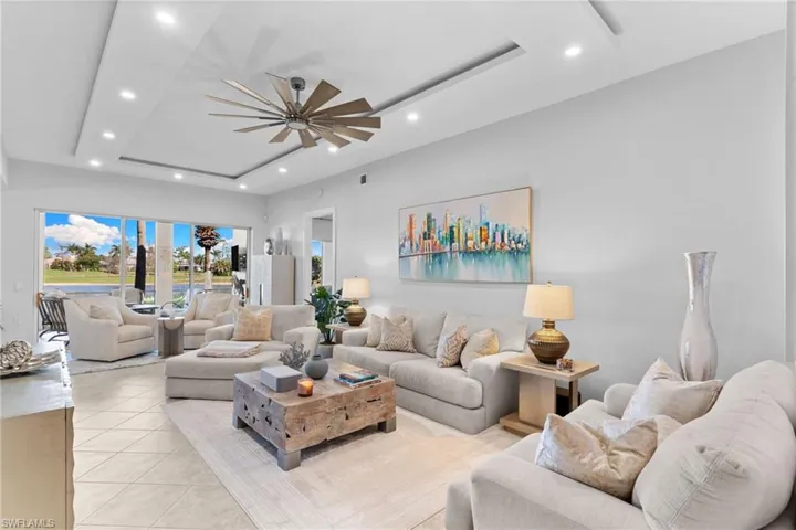 Living area featuring a raised ceiling, ceiling fan, recessed lighting, and light tile patterned flooring