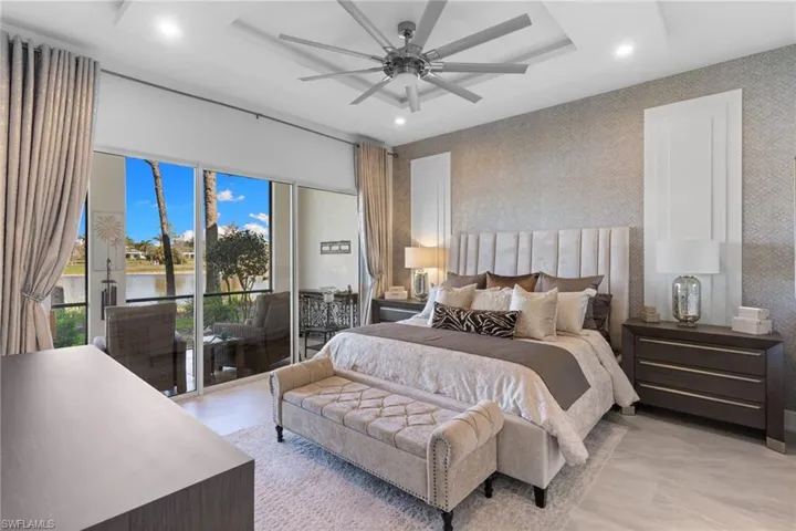 Bedroom featuring access to exterior, recessed lighting, a water view, a ceiling fan, and a raised ceiling