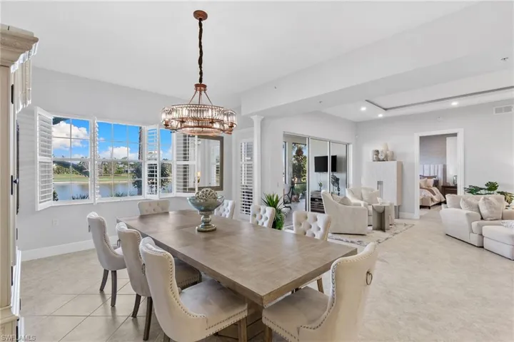 Dining area with a chandelier, a water view, and a tray ceiling