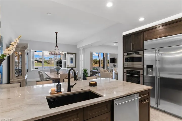 Kitchen featuring dark wood finish cabinets, stainless steel appliances, and light stone counters