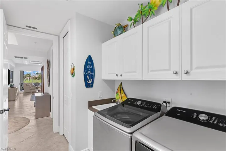 Laundry area with cabinet space, washer and dryer, and light tile patterned floors