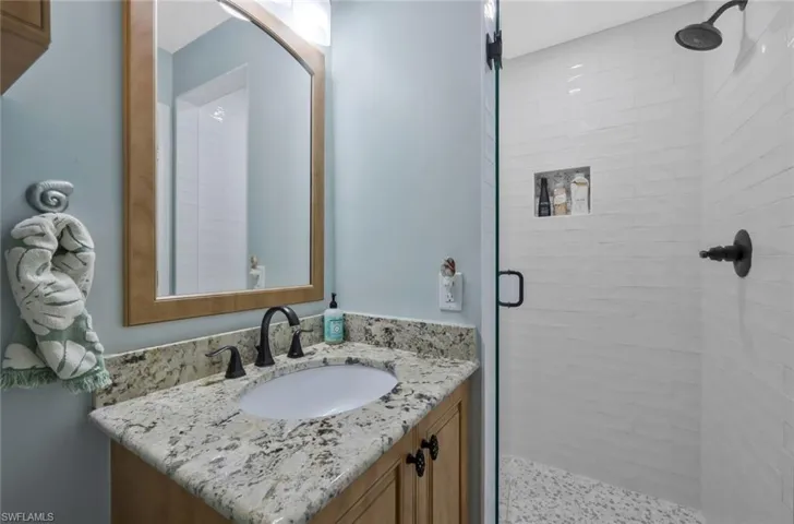 2nd bath hasd a granite coountertop single vanity and walk in shower with floor to ceiling subway tile. Seamless shower door.