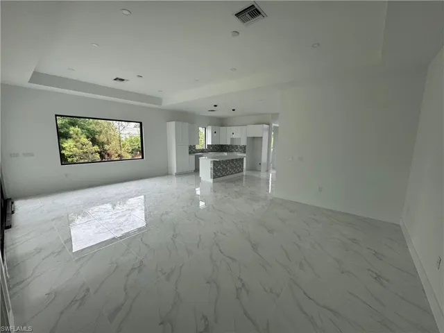 Unfurnished living room featuring a tray ceiling and light tile patterned floors