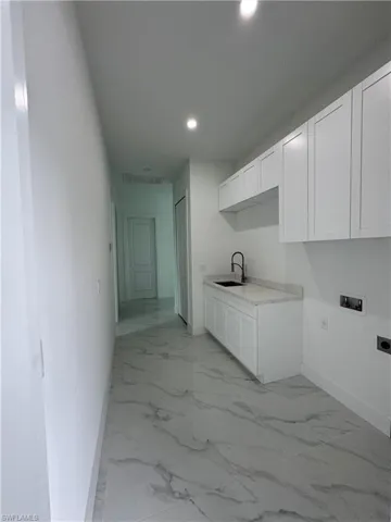 Kitchen with sink, white cabinets, and light tile patterned floors