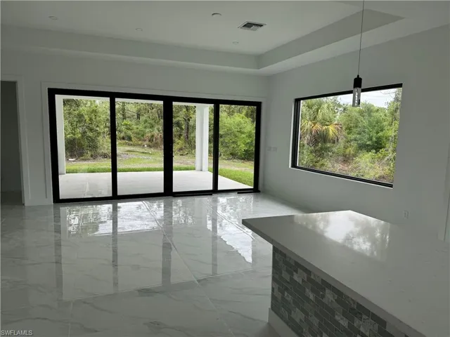 Spare room with light tile patterned floors, a raised ceiling, and a wealth of natural light