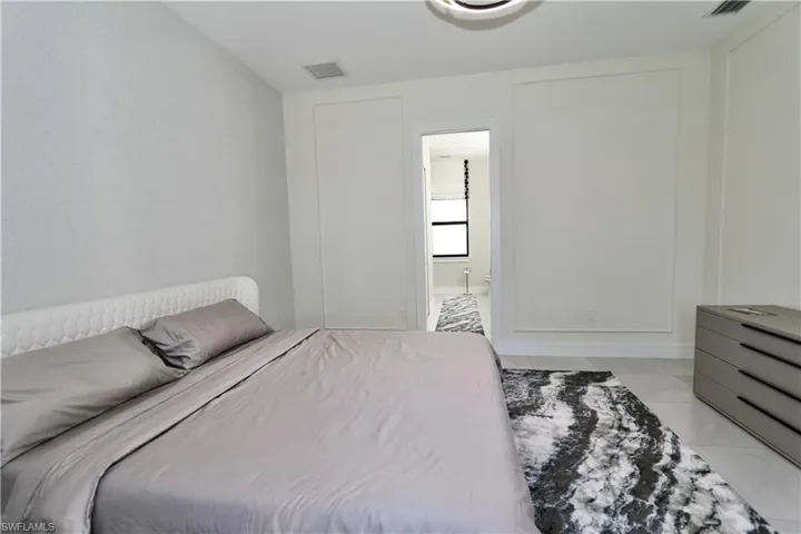 Bedroom with light tile patterned floors and ensuite bath