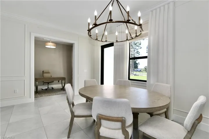 Dining room with suspended lighting, crown molding, and light tile patterned floors