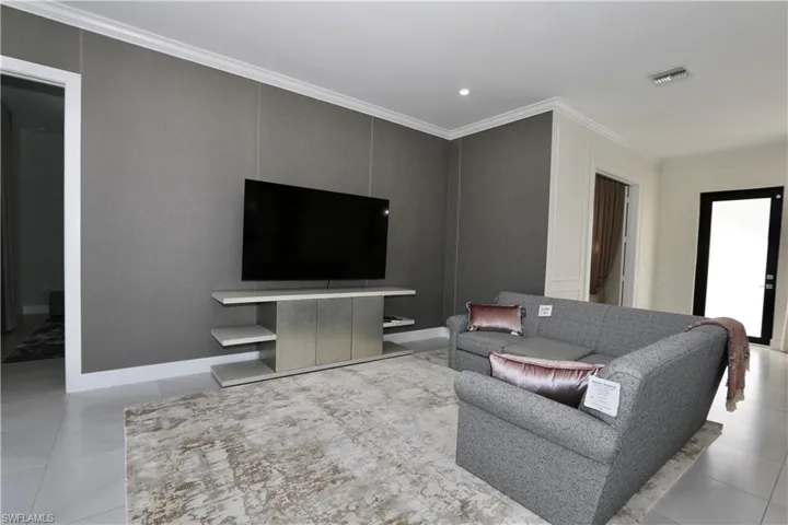 Living room with light tile patterned flooring and ornamental molding