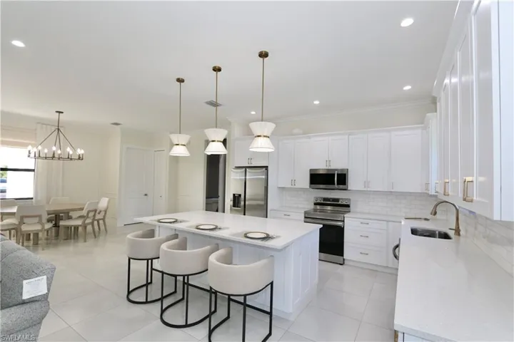 Kitchen featuring stainless steel appliances, white cabinets, a breakfast bar, a center island, and crown molding