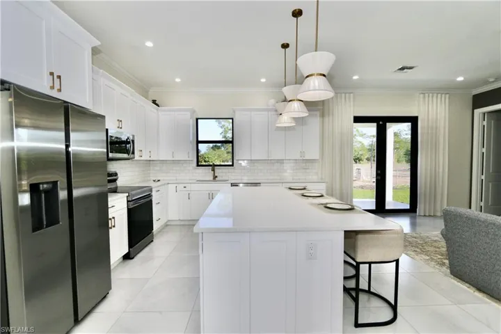 Kitchen with stainless steel appliances, a center island, white cabinets, pendant lighting, and a breakfast bar area