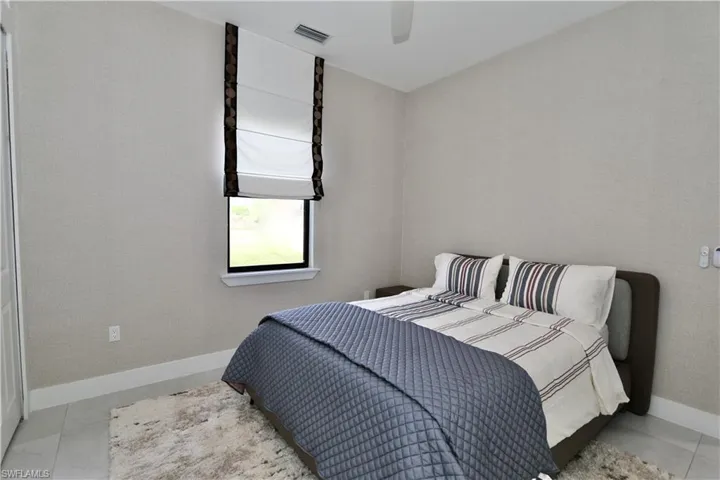Bedroom with ceiling fan and wallpapered walls