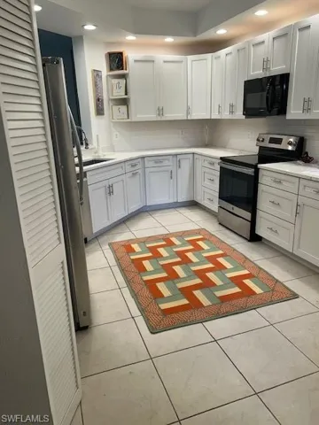 Kitchen featuring range, open shelves, light countertops, light tile patterned floors, and backsplash