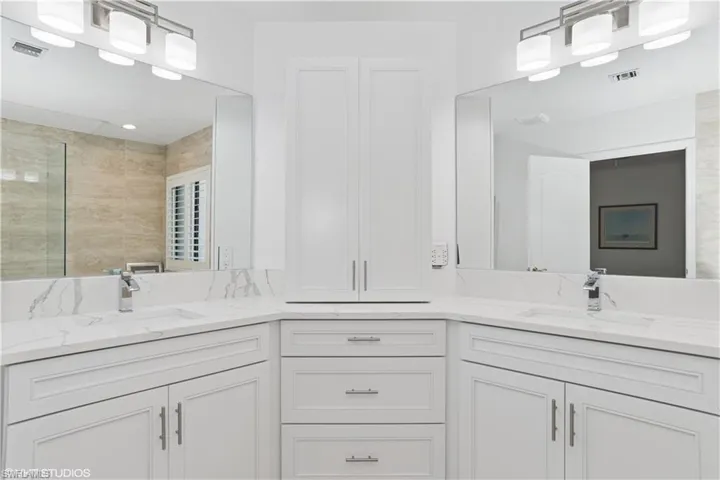 Bathroom with double vanity, visible vents, a tile shower, and a sink