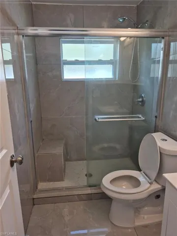 Bathroom featuring vanity, an enclosed shower, and toilet