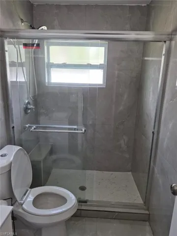 Bathroom with an enclosed shower, vanity, and toilet