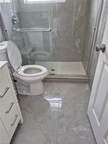 Bathroom featuring vanity, a shower with shower door, and toilet