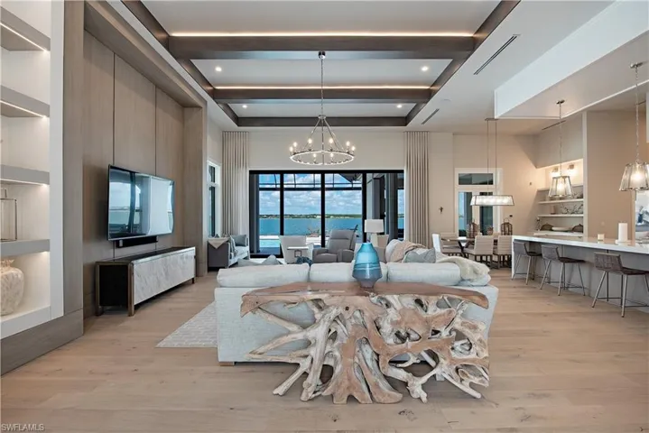 Dining area with an inviting chandelier, beam ceiling, light wood-style floors, a towering ceiling, and visible vents