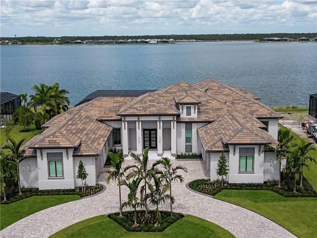 French country home with a water view, curved driveway, french doors, and stucco siding