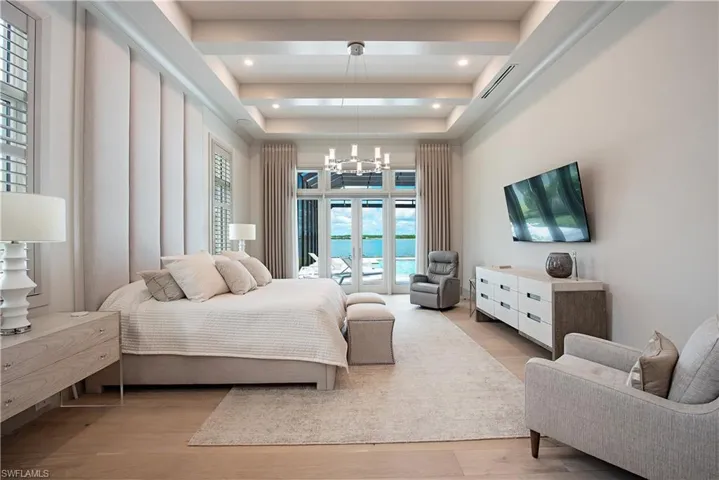 Bedroom with wood finished floors, a raised ceiling, a chandelier, access to outside, and recessed lighting