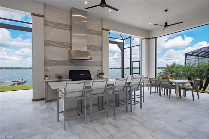 View of patio featuring glass enclosure, a water view, and outdoor wet bar