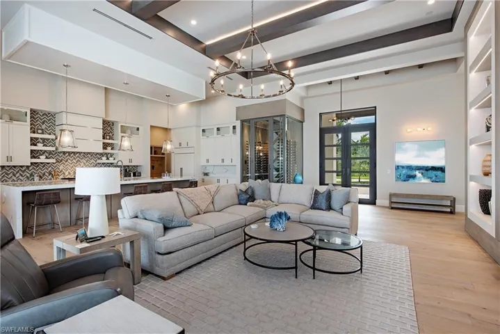 Living room featuring recessed lighting, beamed ceiling, light wood-type flooring, and a chandelier