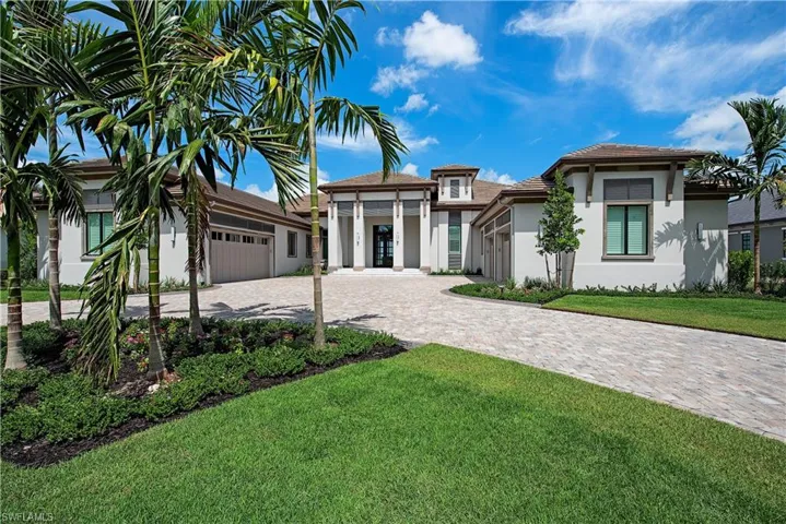 View of front of property featuring a garage, decorative driveway, stucco siding, and a front yard