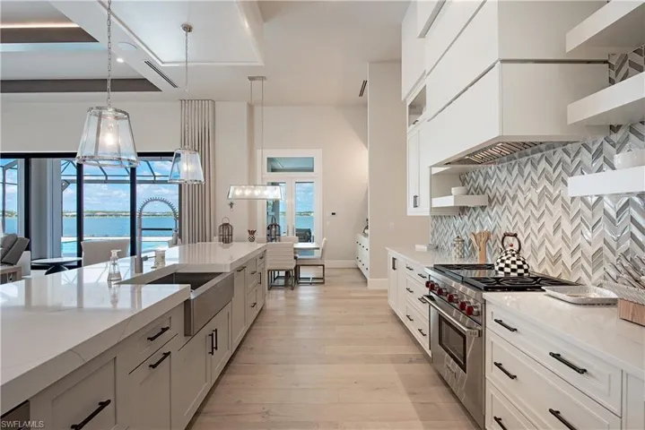 Kitchen with plenty of natural light, decorative backsplash, a sink, and high end stove