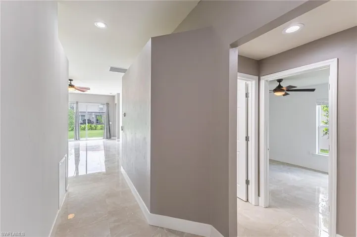 Hallway with plenty of natural light, light marble finish floors, and recessed lighting