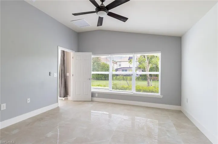 Empty room featuring plenty of natural light, vaulted ceiling, and a ceiling fan