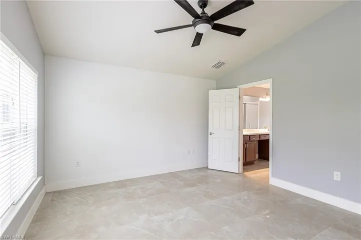 Unfurnished bedroom featuring vaulted ceiling and ensuite bathroom