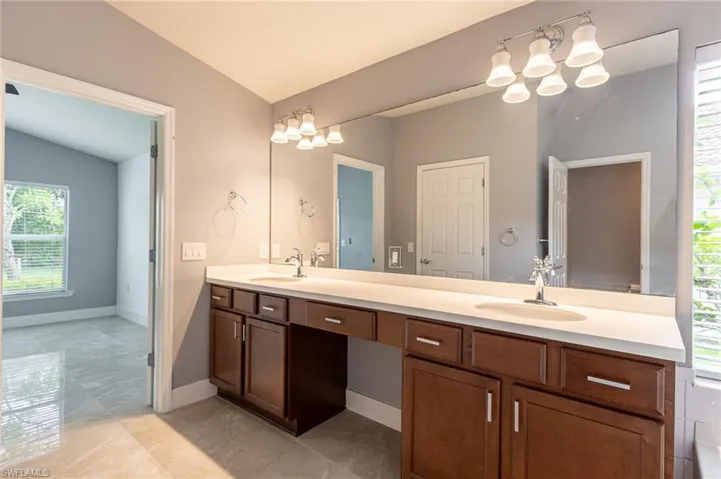 Full bathroom with vaulted ceiling, double vanity, and a chandelier