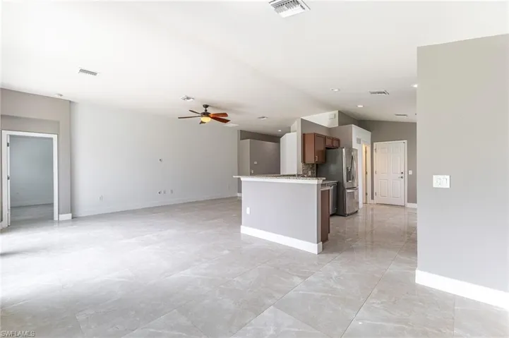Kitchen with stainless steel refrigerator with ice dispenser, a ceiling fan, open floor plan, light marble finish flooring, and recessed lighting
