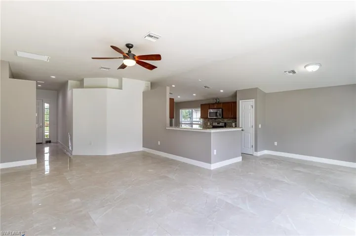 Unfurnished living room featuring a ceiling fan, healthy amount of natural light, light marble finish flooring, and recessed lighting