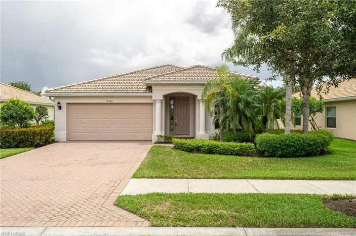 Mediterranean / spanish house with an attached garage, decorative driveway, stucco siding, a tiled roof, and a front lawn