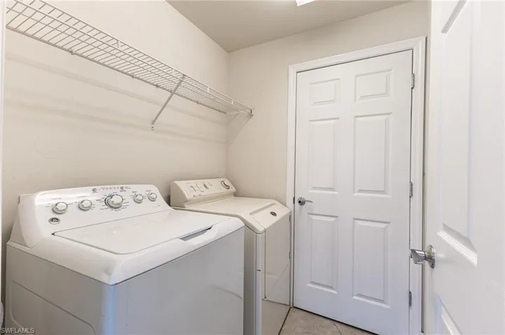 Washroom with washer and dryer and light tile patterned floors