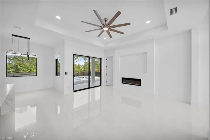 Spare room featuring a raised ceiling, a glass covered fireplace, and a ceiling fan