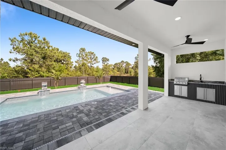 View of pool featuring an outdoor kitchen, a ceiling fan, area for grilling, a fenced backyard, and a sink