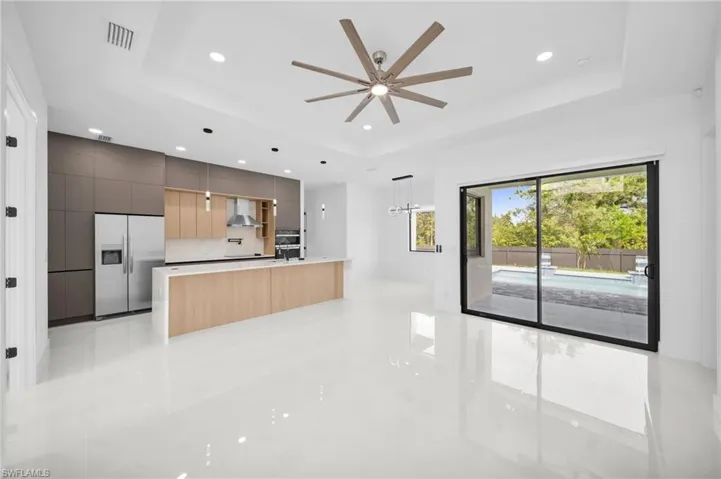 Kitchen with wall chimney exhaust hood, modern cabinets, a tray ceiling, visible vents, and built in fridge