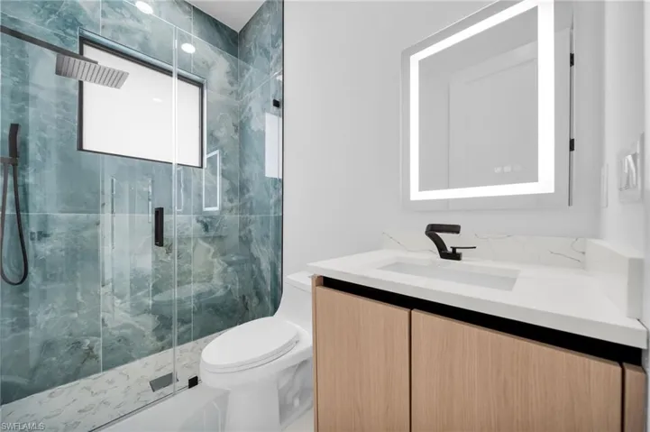 Bathroom with vanity, a marble finish shower, and toilet