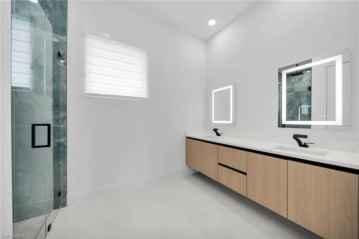 Bathroom with double vanity, a sink, and a marble finish shower