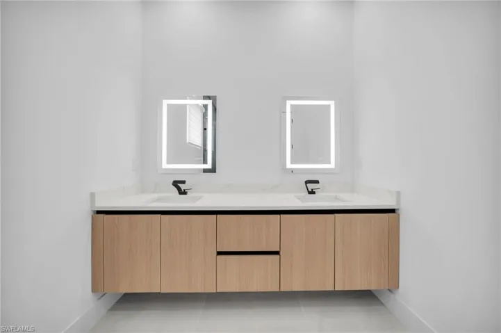 Bathroom with a sink, baseboards, and double vanity
