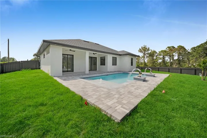 Rear view of property featuring a fenced backyard, stucco siding, a ceiling fan, and a lawn